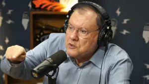 Jornalista Milton Neves com fones e microfone em programa de rádio